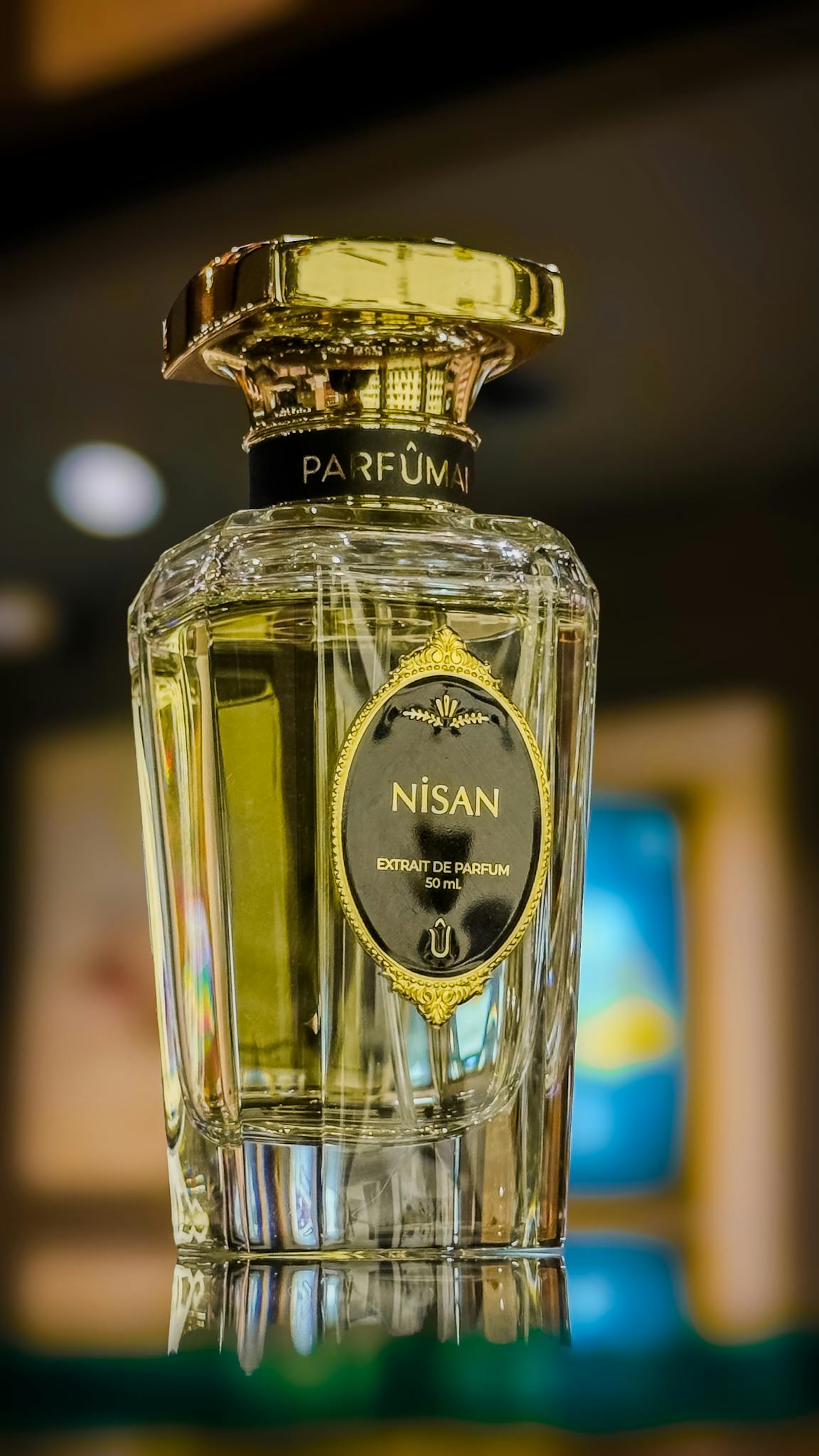 Crystal bottle of Nisan perfume with gold details on a blurred background.